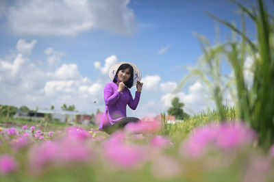 Woman standing on purple flowering plants on field