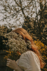 Rear view of woman standing against trees