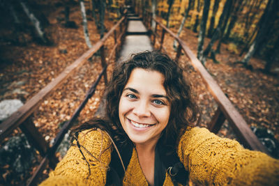 Portrait of young woman sitting on railing