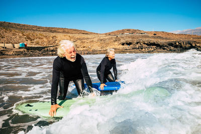 Senior couple surfing in sea