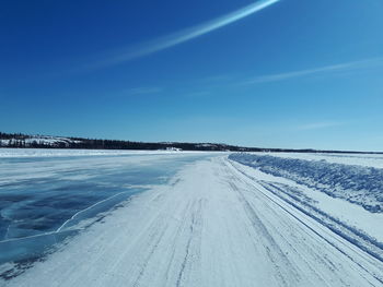 Snow covered land against blue sky