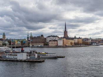 Boats sailing in river with city in background