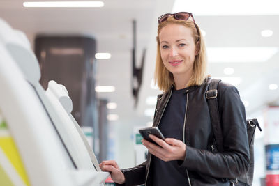 Portrait of beautiful woman using atm at airport