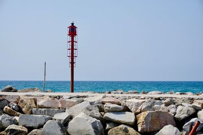 Lighthouse by sea against clear sky