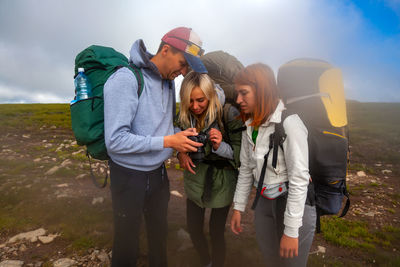 Hiking man and women with backpack enjoys a hike and looks at the pictures taken on camera 