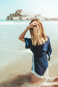 Side view of woman standing in sea against sky