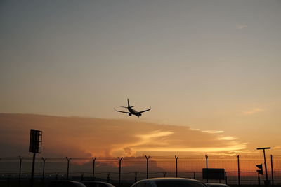 Low angle view of silhouette airplane against sky during sunset