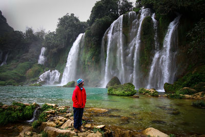 Woman standing against waterfall