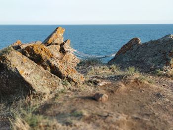 Rocks on shore by sea against sky