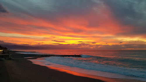 Scenic view of sea against dramatic sky during sunset