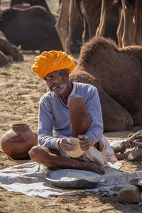 Mature man preparing food at desert during sunny day