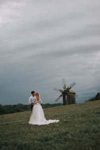 Couple kissing on grass against sky