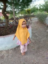 Rear view of girl standing against yellow wall