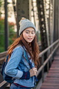 Portrait of beautiful young woman standing against railing