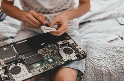 A young man is changing the thermal paste on a laptop.