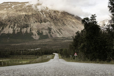 Road by mountains against sky