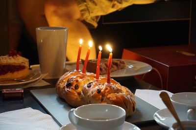 Close-up of lit candles on bread at table