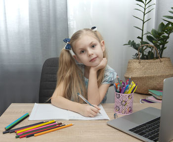 Portrait of young woman sitting on table at home