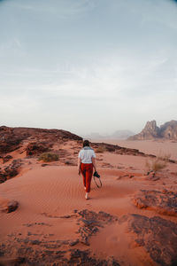 Rear view of young woman walking on field