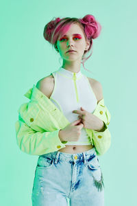 Portrait of young woman with arms crossed standing against blue background