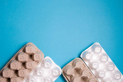 Several foam and cardboard packaging for eggs on a blue background, sorting waste concept