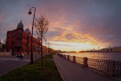 Road passing through city at sunset