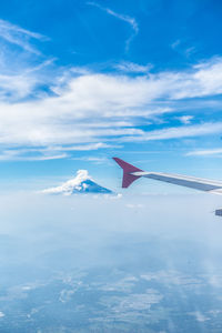 Aerial view of airplane flying over water against blue sky