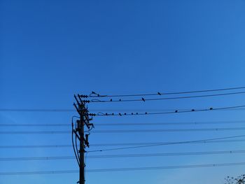 Low angle view of power lines against clear blue sky