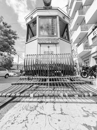 Railroad tracks by street in city against sky