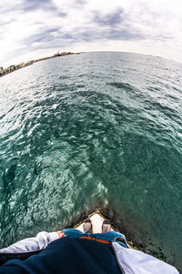 Low section of man lying on sea shore against sky