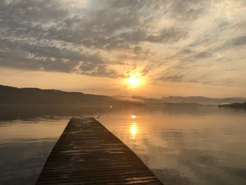 Pier over lake against sky during sunset