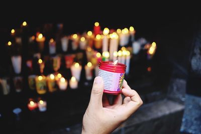 Midsection of person holding illuminated candles