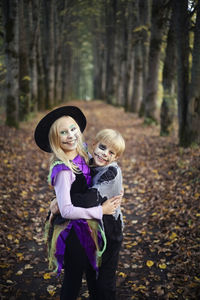 Portrait of cute halloween girl and boy standing in forest  