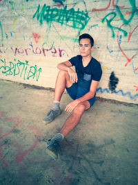 Portrait of young man sitting on wall