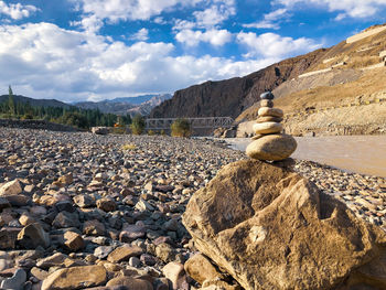 Stack of stones on shore against sky