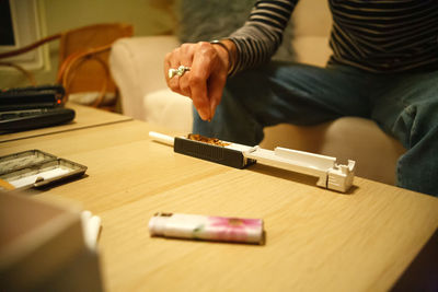 Woman rolling tobacco cigarettes with tool