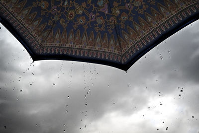 Close-up of wet glass against sky during rainy season