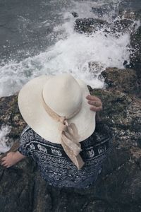 High angle view of woman holding rock by sea