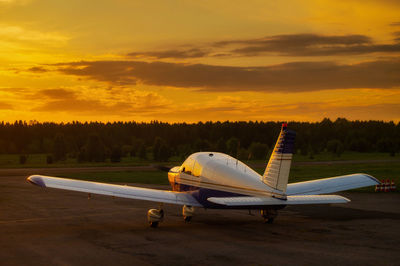 Airplane at airport against sky during sunset