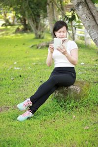 Young woman using mobile phone in field