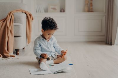 Boy looking up while sitting on floor at home