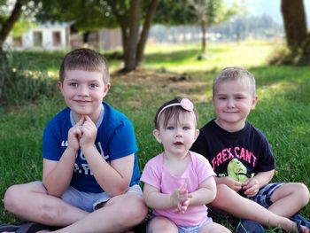 Portrait of brothers and sister sitting on field