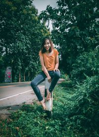 Portrait of smiling young woman sitting against plants