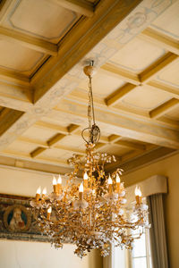 Low angle view of illuminated chandelier hanging on ceiling in building