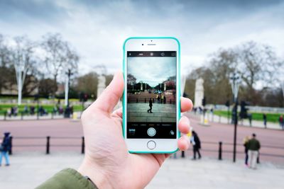 Cropped image of man photographing through smart phone