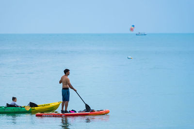 Rear view of men in sea against sky