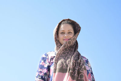 Portrait of a smiling young woman against clear blue sky