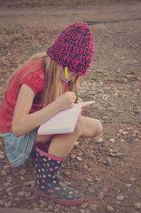 Full length of girl drawing in book on field