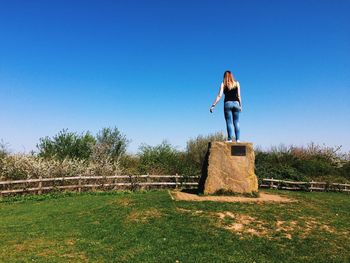 Woman standing on field against clear blue sky