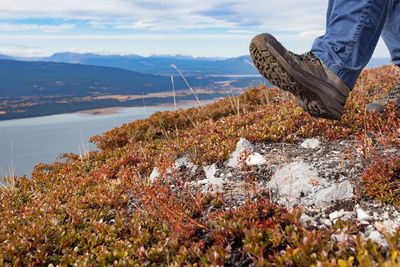 Low section of person on rock against sky